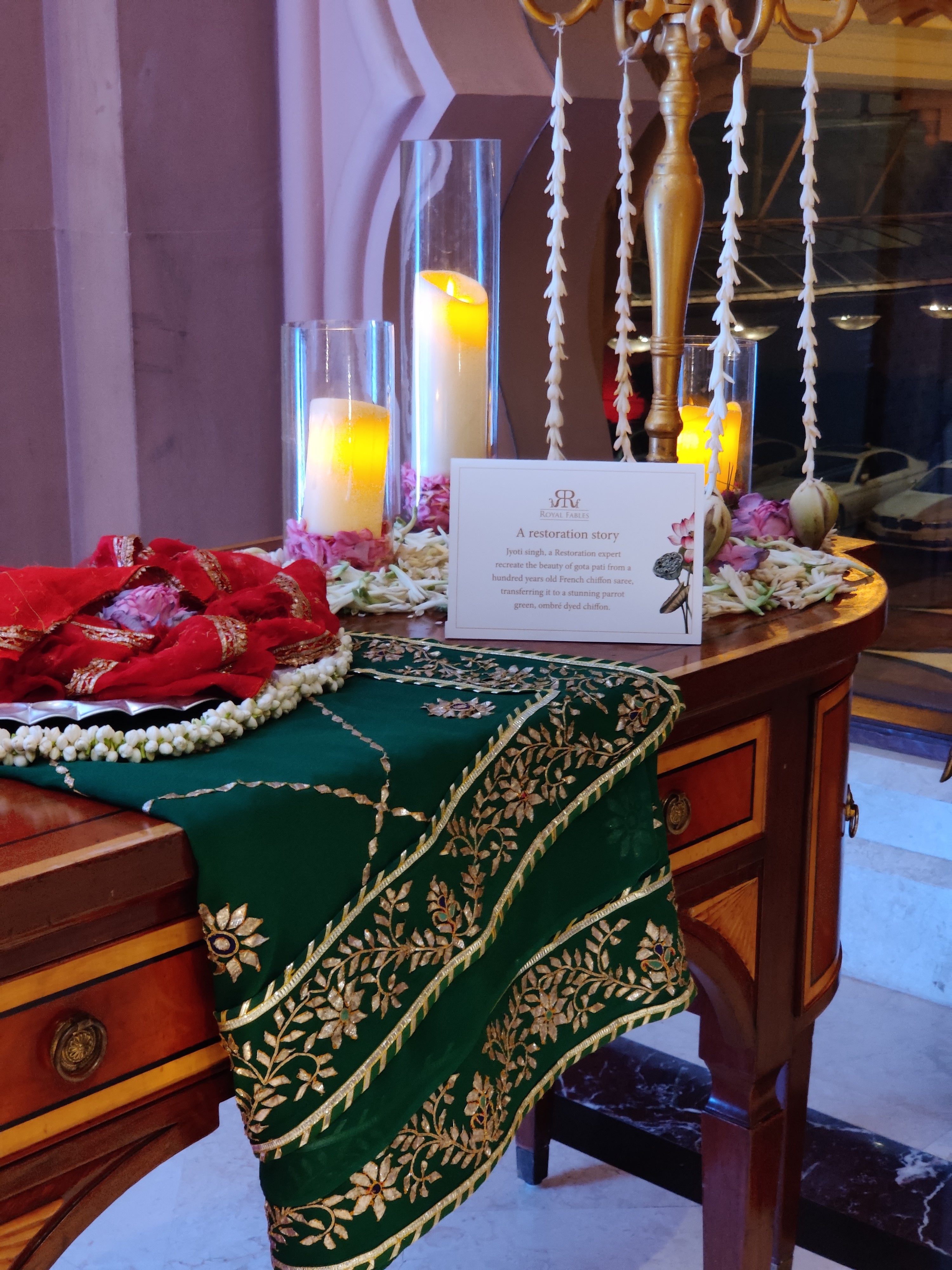 Restored Gotapatti Saree displayed with flowers and candles on a vinatge wooden table