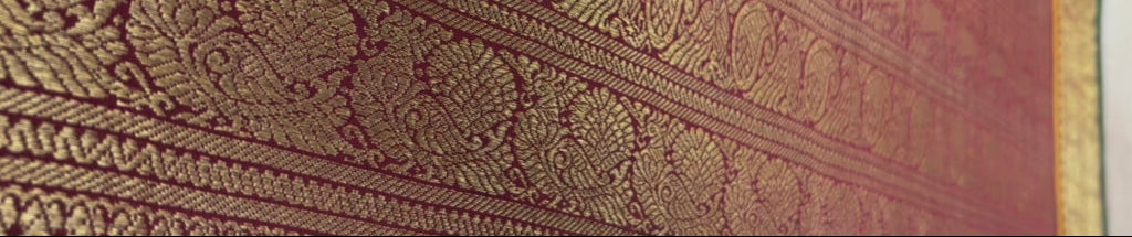 Close-up of a Kanjeevaram border with peoacock and deer designs on a red background